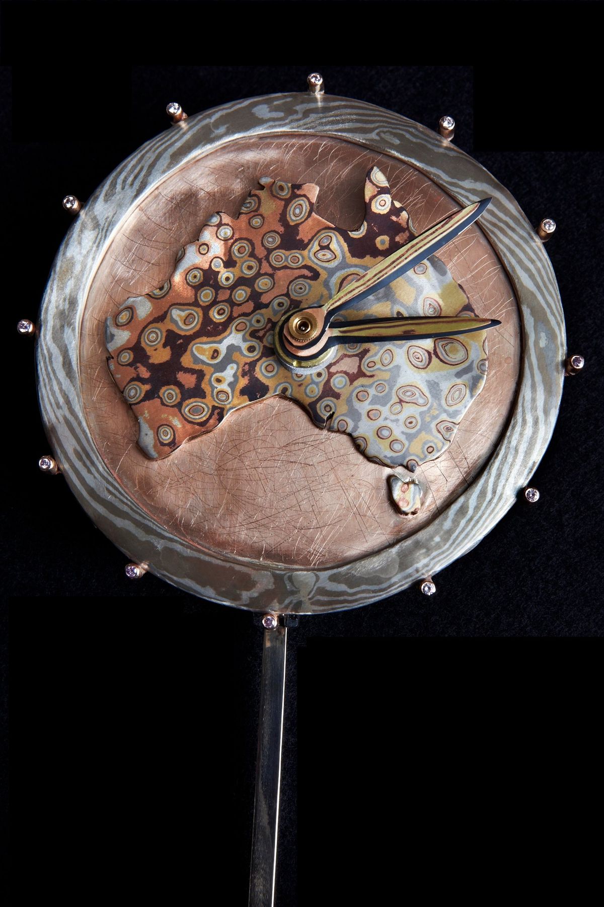 The clock face: the map of Australia in swirling Mokume Gane on the rose gold dial, with the gold hands