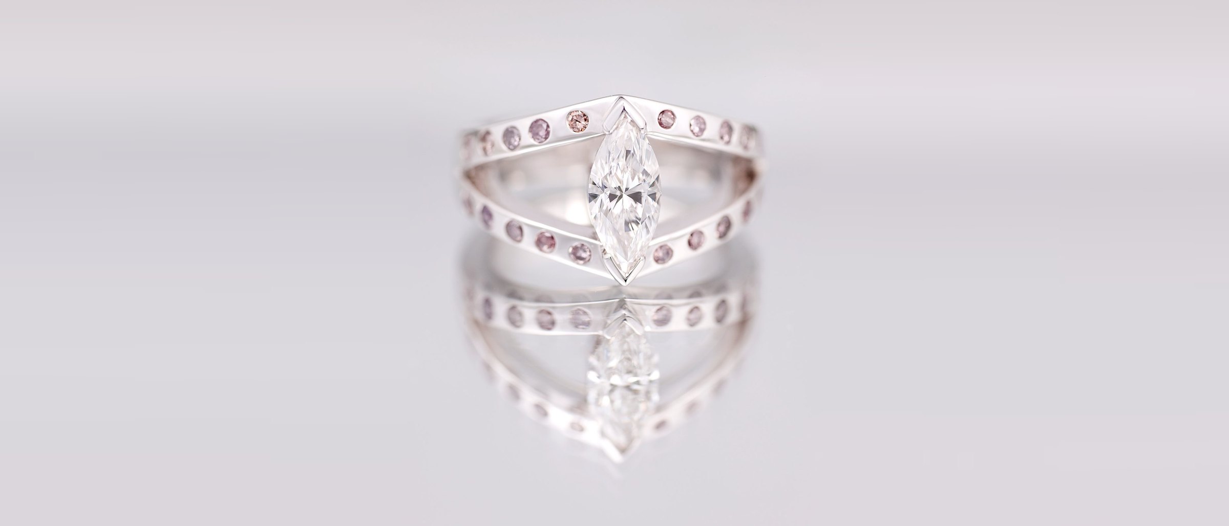 A marquise diamond held between two diamond-set chevron bands in white gold