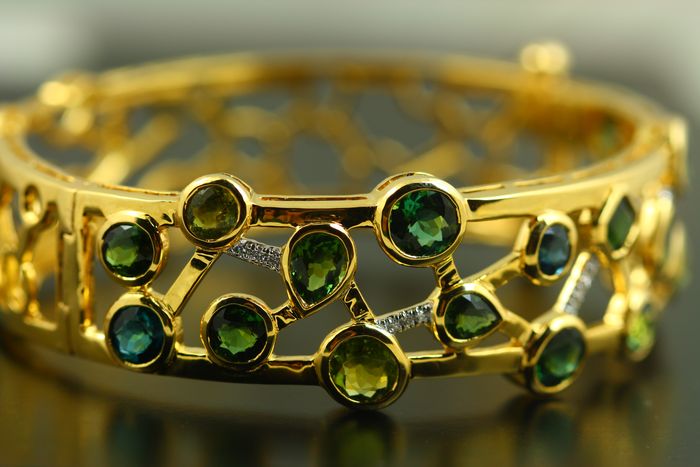 Tourmaline and diamond lattice cuff: green Tourmalines and diamonds interlinked in an 18 karat yellow gold cuff