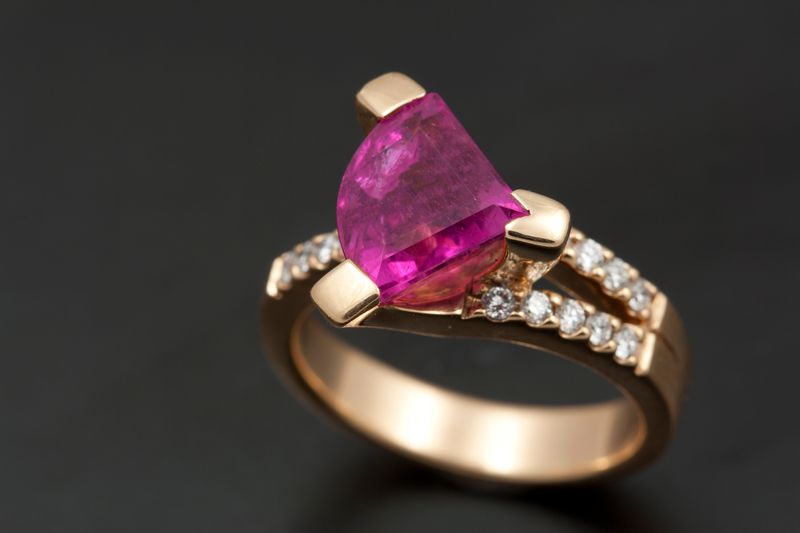 A rose gold ring with a triangular pink tourmaline and a curve of diamonds