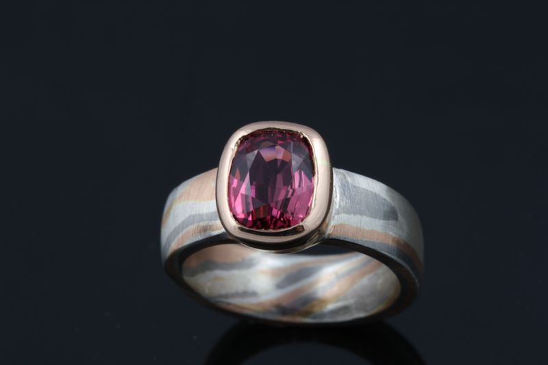 A cushion-cut pink tourmaline set on a Mokume Gane band, on black