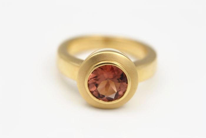 Peach Sapphire ring: a peach Sapphire set in 18 karat yellow gold