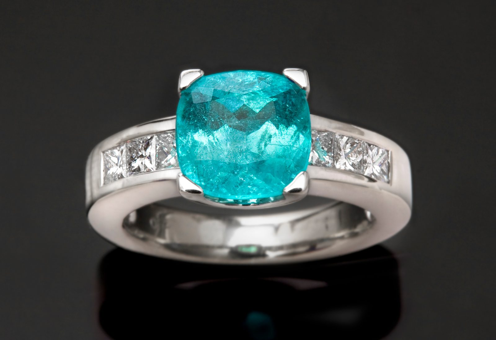 A Brazilian Paraiba tourmaline ring in white gold with princess-cut diamonds, on black