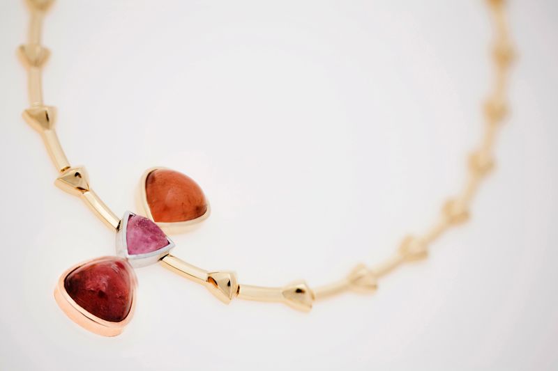 A gold chain necklace with two triangular pink tourmalines at the centre