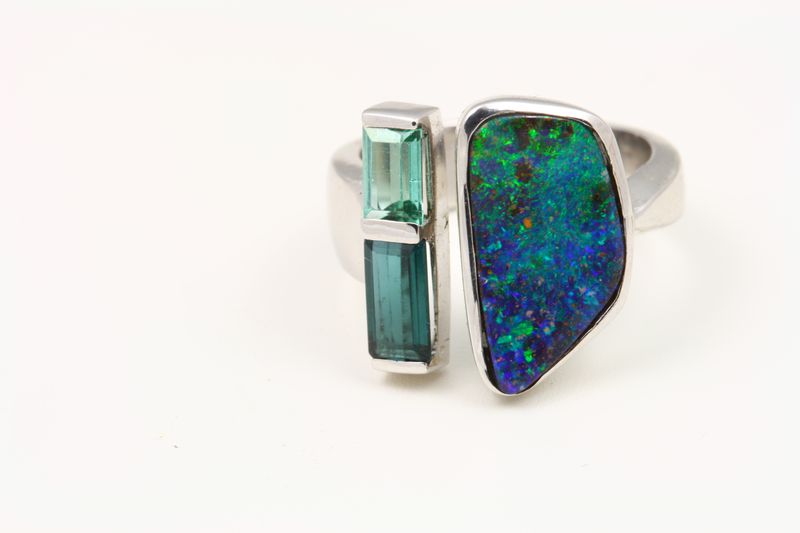 A ring pairing a free-form boulder opal with two green tourmaline bars