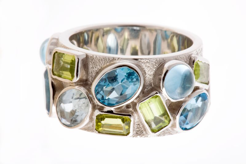 A wide silver band set with pale blue and green stones, seen from the side