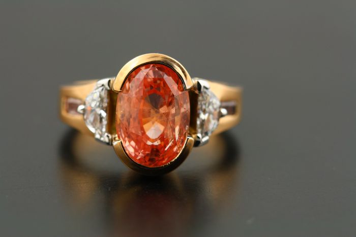 Padparadscha Sapphire ring: Padparadscha Sapphire set in 18 karat rose gold with two half-moon diamonds and two baguette cut pink diamonds