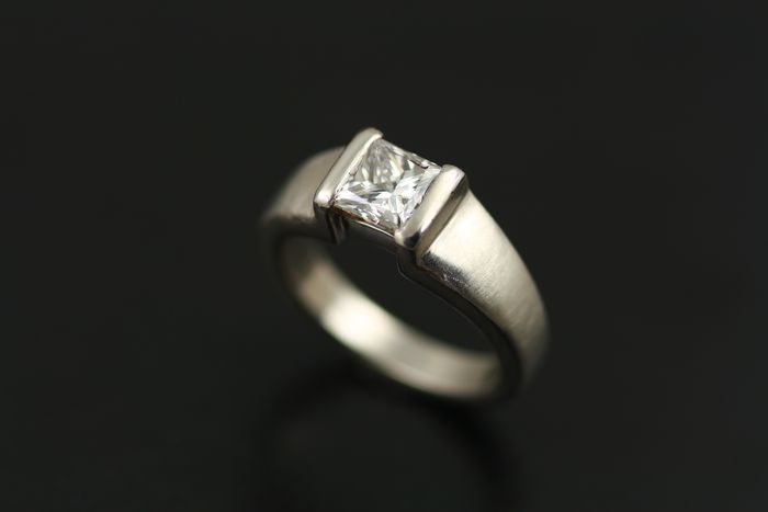 Princess cut diamond ring: a princess cut diamond set in an open bezel setting of matte finished white gold