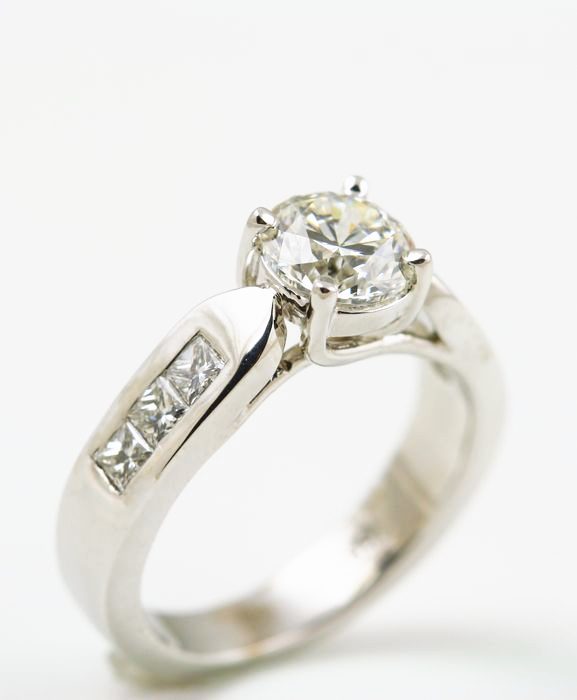 Diamond solitaire: a diamond with princess cut diamonds in 18 karat white gold
