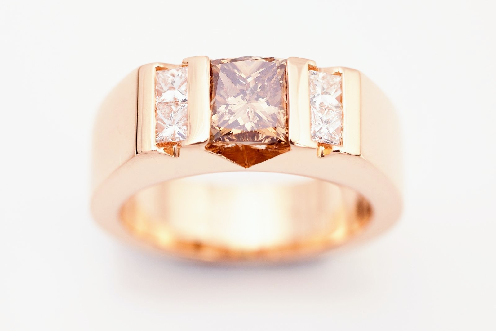 A rose gold band with a cushion-cut champagne diamond flanked by princess diamonds