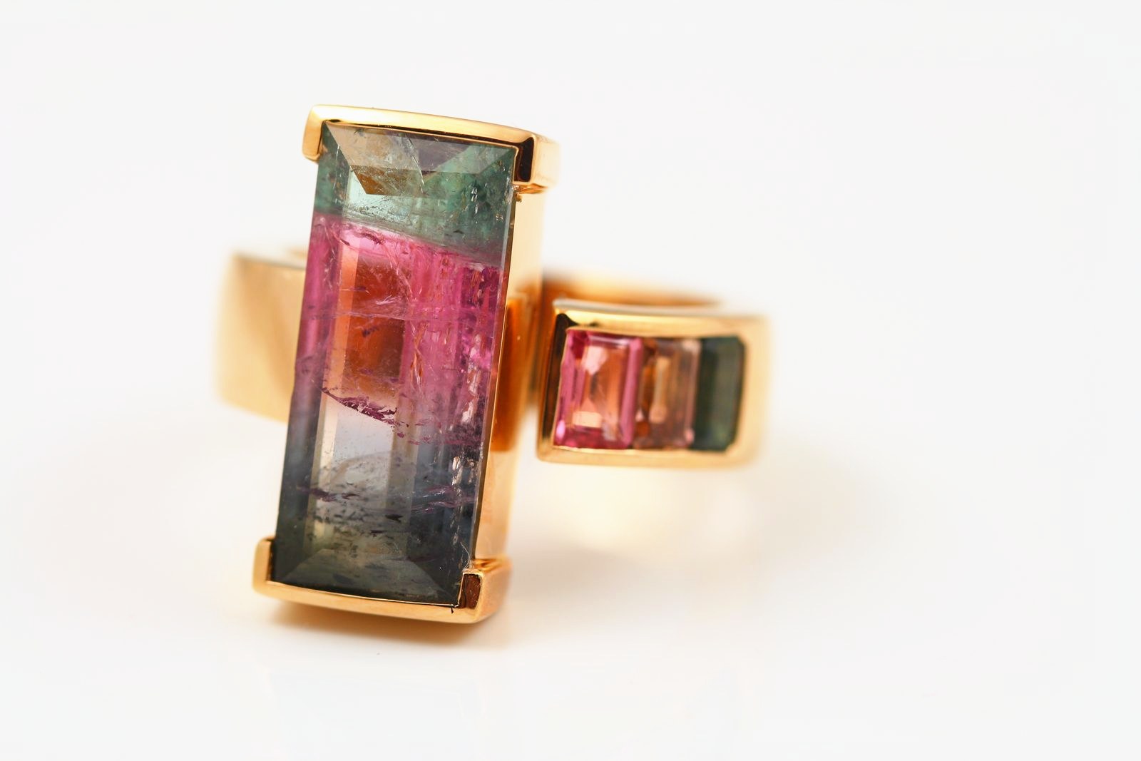 A ring with a long bar of green-to-pink watermelon tourmaline beside a small pink tourmaline