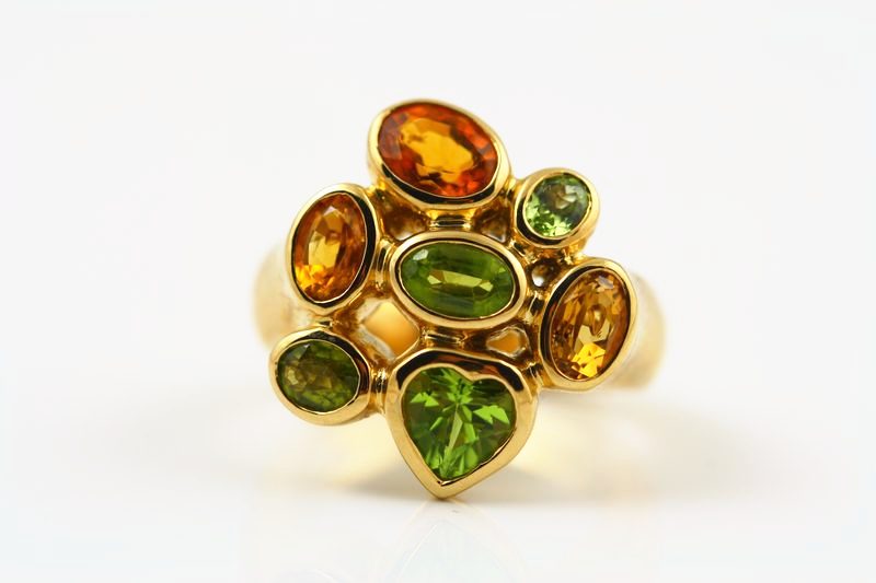 A yellow gold ring with a cluster of orange, green and golden stones