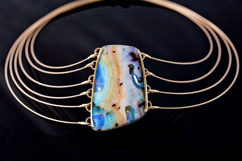 A collar of five fine gold wires fanning around a rectangular boulder opal
