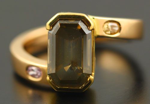 Fancy coloured diamond ring: a brownish greenish yellow diamond with a pink diamond and an orange diamond in 18 karat rose and yellow gold