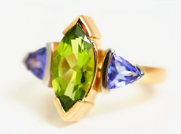 Peridot three-stone ring: a Peridot with Tanzanites in 18 karat yellow gold