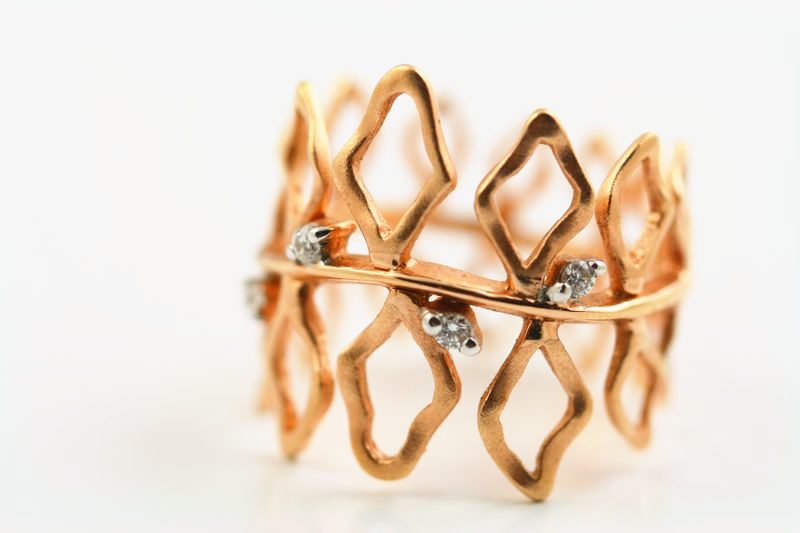 An open lattice band in rose gold with a few small diamonds at the crossings