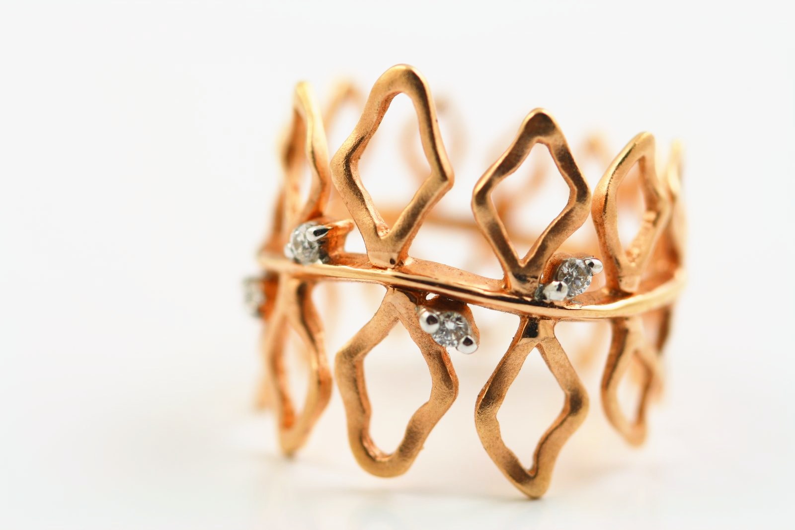 An open lattice band in rose gold with a few small diamonds at the crossings